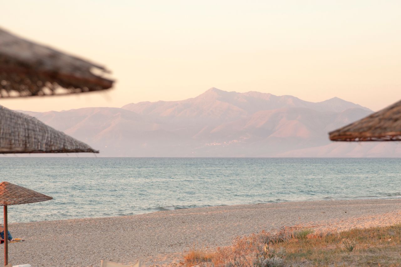 Plaža na ostrvu Krf tokom sumraka sa planinom u pozadini