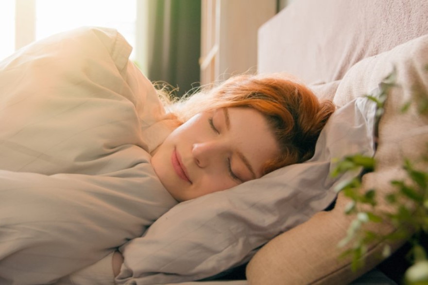 Devojka spava u krevetu ispod ćebeta