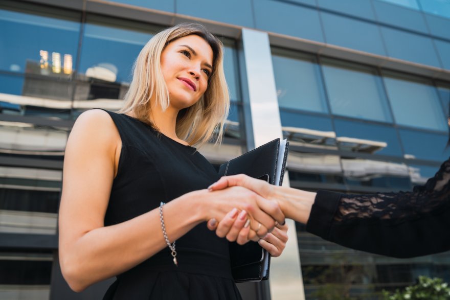 Biznisžena se rukuje sa osobom ispred solitera